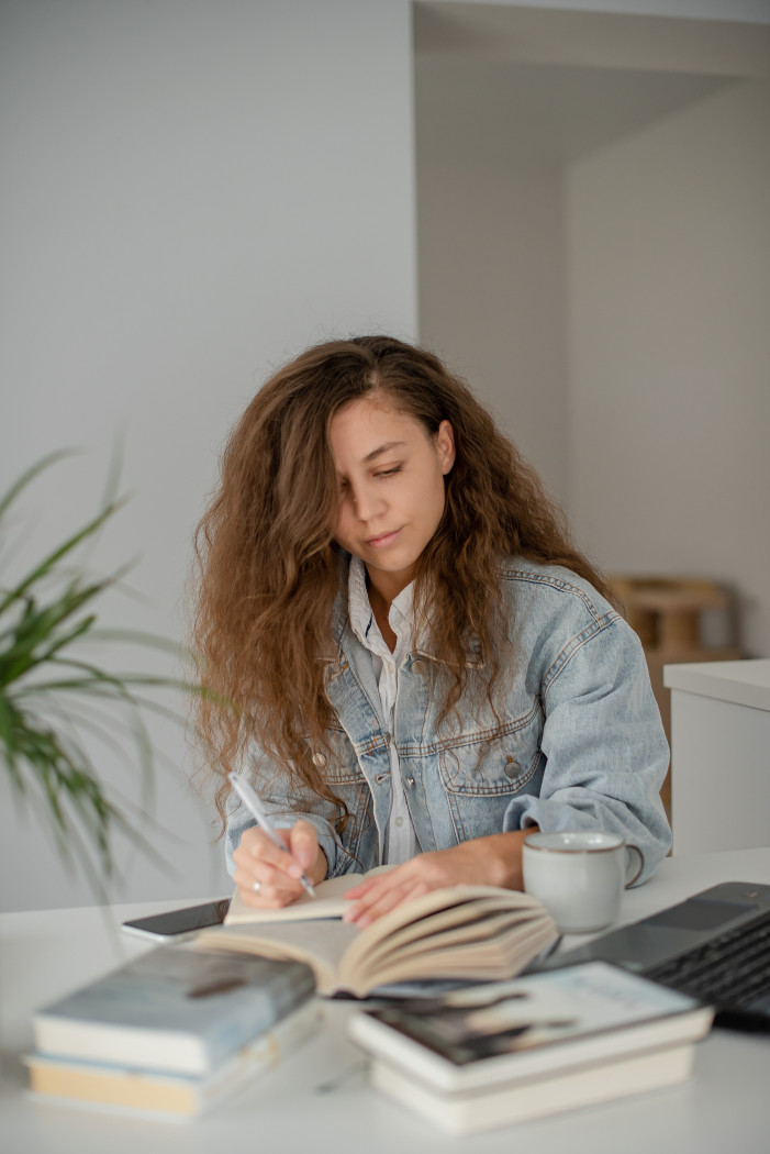 girl surrounded by books writing in notebook inner growth confidence